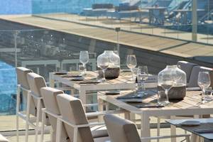 Außenterrasse des ME Ibiza Hotels mit Tisch und Gläsern vor Meerblick.