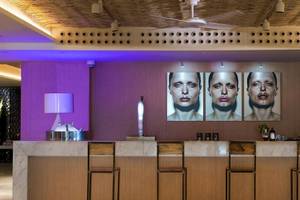 Innenansicht der Bar im ME Ibiza Hotel mit drei Porträts an der Wand, Barhockern und einer Lampe.