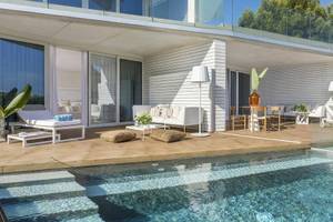 Außenbereich des ME Ibiza Hotels mit Swimmingpool, Loungemöbeln und Glaswänden