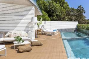 Terrasse des ME Ibiza Hotels mit Swimmingpool, weißen Möbeln und grünen Pflanzen.