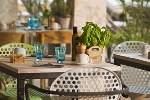 Restauranttisch im ME Ibiza Hotel mit grünen Stühlen und Holztisch.