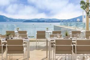Terrasse des ME Ibiza Hotels mit Blick auf das Meer und Berge