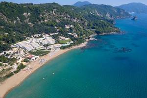 Luftaufnahme des Pelekas Klosters mit Blick auf eine blaue Bucht und einen Sandstrand