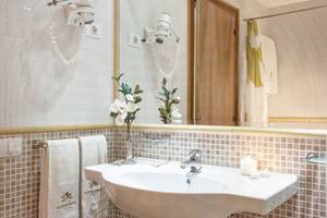 Badezimmer des Sotavento Beach Club Hotels mit gefliester Wand, Waschbecken und Spiegel.