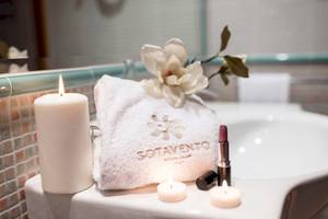 Badezimmer im Sotavento Beach Club mit einem Handtuch, Blumen, Kerzen und Kosmetik