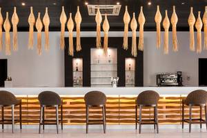 Barbereich des Mitsis Faliraki Beach Hotel & Spa mit modernen Stühlen und goldfarbenen Beleuchtungselementen