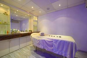 Spa-Behandlungsraum im Golden Bay Beach Hotel mit Massagetisch, Handtüchern und Aromatherapie-Steinen.