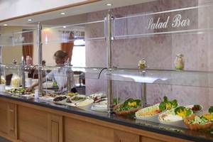 Salatbar im Mitsis Rinela Beach Hotel mit verschiedenen Salaten und einer Mitarbeiterin.