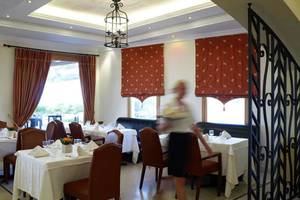 Innenansicht des Restaurants des Mitsis Rinela Beach Hotels mit Tisch und Stühlen.