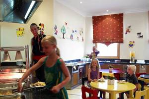 Frühstücksbuffet im Mitsis Rinela Beach Hotel mit Kindern, die Speisen servieren.