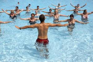 Gruppe von Schwimmern, die Wassergymnastik im Pool des Mitsis Rinela Beach Hotels machen.