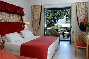 Zimmer im Mitsis Rinela Beach Hotel mit Blick auf eine Terrasse und einen Garten.