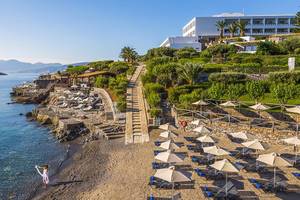 Luftaufnahme des Minos Palace Hotel & Suites mit Blick auf den Strand, Liegestühlen und Sonnenschirmen.