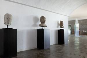 Drei Buddha-Kopf-Skulpturen auf schwarzen Sockeln im Minos Palace Hotel & Suites.