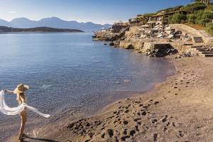 Frau im Bikini am Strand vor dem Minos Palace Hotel & Suites