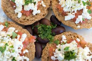 Griechisches Brot mit Tomaten und Fetakäse, serviert mit Oliven und Kräutern.