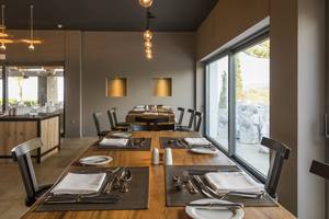 Innenbereich des Minos Palace Hotel & Suites Restaurants mit gedeckten Tischen und Blick auf die Außenterrasse.