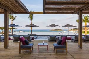 Außenbereich des Minos Palace Hotel & Suites mit Blick auf das Meer und Loungemöbeln.