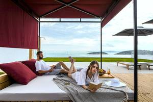 Paar auf Bett im Freien im Minos Palace Hotel & Suites mit Meerblick