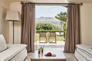 Innenraum der Minos Palace Hotel & Suites mit Blick auf eine Terrasse und Garten