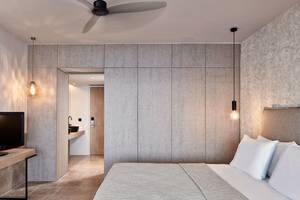 Schlafzimmer des Minos Palace Hotel & Suites mit Fernseher, Bett und Einbauschränken