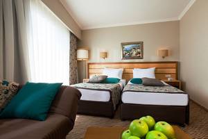Doppelbettzimmer im Side Sun Hotel mit zwei Betten, Kissen, Couch und Obstschale.