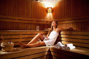 Eine Frau im weißen Badetuch sitzt entspannt in der Sauna des Side Sun Hotels.