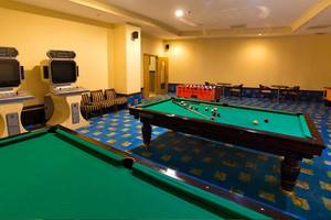 Spielzimmer im Side Sun Hotel mit zwei Billardtischen, Spielkonsolen und Tischen.