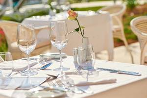 Essen-Tisch im Hipotels Playa de Palma Palace mit Gläsern, Besteck und einer Rose in einer Vase.