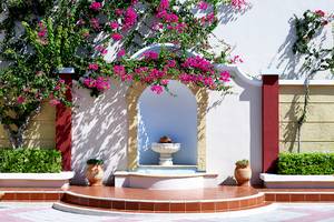Eingang des Mitsis Summer Palace Beach Hotels mit blühenden Bougainvillea und Brunnen