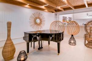 Loungebereich im Insula Alba Resort & Spa mit einem Klavier, Rattanmöbeln und einer Wanddekoration.