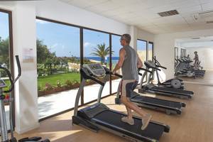 Ein älterer Mann läuft auf einem Laufband im Fitnessstudio mit Blick auf das Meer.