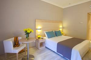 Hotelzimmer im Domes of Corfu, Autograph Collection mit Bett, Tisch und Blumenvase.