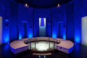 Jacuzzi im Ritz-Carlton Ras Al Khaimah, Al Wadi Desert, mit blauer Beleuchtung und runden Bänken.