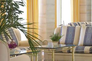 Loungebereich im Lindos Princess Beach Hotel mit blau-weiß gestreiften Sofas und Glastisch.