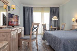 Ein Hotelzimmer im Lindos Princess Beach Hotel mit Bett, Schreibtisch, Fernseher und Möbeln.