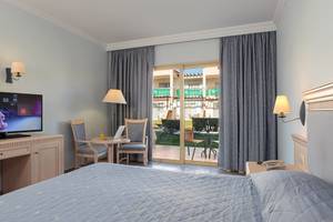 Hotelzimmer im Lindos Princess Beach mit Fernseher, Schreibtisch und Terrassenzugang.