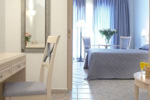 Innenansicht eines Zimmers im Lindos Princess Beach Hotel mit Bett, Schreibtisch und Möbeln.
