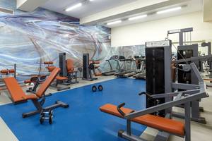 Fitnessbereich im Lindos Princess Beach Hotel mit Geräten und einer blauen Trainingsfläche.