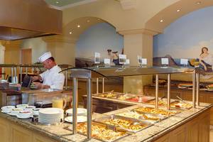 Buffet im Lindos Princess Beach Hotel mit einem Koch, der Essen zubereitet und serviert.