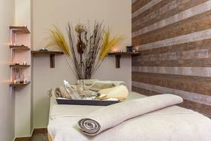 Spa-Behandlungsraum im Lindos Princess Beach Hotel mit Holzwand und Behandlungsliege.