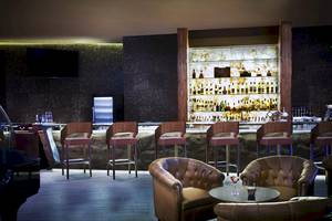 Barbereich im Sofitel Dubai The Palm mit Holzstühlen und einer großen Bar.