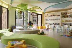 Kinderzimmer im Sofitel Dubai The Palm mit grünen Möbeln, Bücherregalen und Spielsachen.