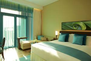 Hotelzimmer im Sofitel Dubai The Palm mit großem Bett, Sofa und Fenstern.