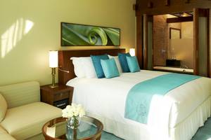 Schlafzimmer im Sofitel Dubai The Palm mit blauen Kissen und einem großen Bett.