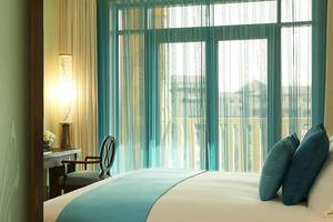 Ein Hotelzimmer mit einem Bett, das auf die Stadt mit Gebäuden und Bäumen draußen blickt.