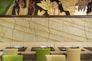 Innenansicht des Restaurants im Sofitel Dubai The Palm mit kunstvollen Wandmalereien und gedeckten Tischen.