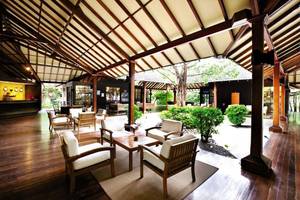Innenbereich des Hotel-Loungs mit Holzboden, weißen Sesseln und Tischen sowie einem großen Dach.