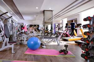 Fitnessstudio im Pickalbatros White Beach Resort mit verschiedenen Geräten und einer Person, die auf einem Laufband läuft.