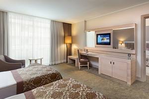 Doppelzimmer im Miracle Resort mit zwei Betten, Schreibtisch, Fernseher und einem Wohnzimmerbereich.